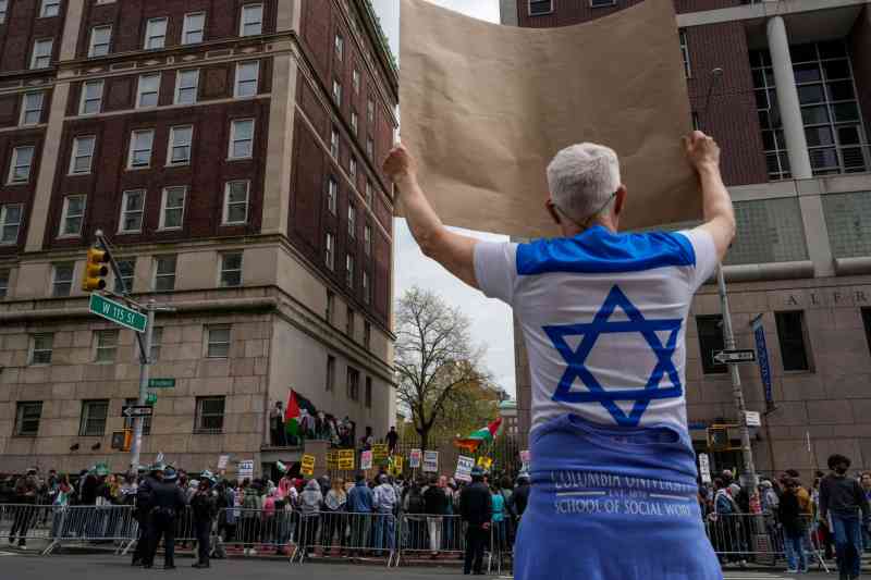 Un contramanifestante pro-israelí muestra un cartel hacia la manifestación en Columbia